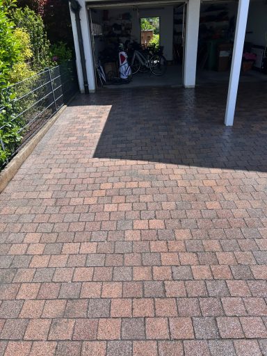 Pflasterung mit rechteckigen Steinen in Einfahrt, Garage im Hintergrund sichtbar.