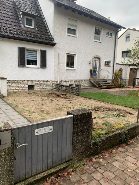 Einfamilienhaus mit Garten, unbefestigter Fläche und Zugangstür.