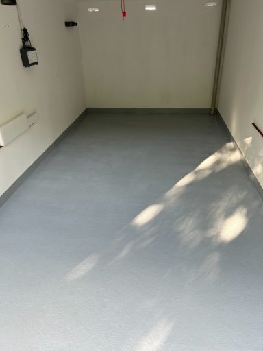 Glatte, graue Bodenfläche in einem leeren Raum mit schwachem Licht.