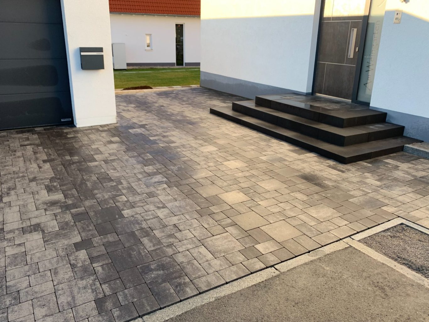 Treppe aus schwarzen Stufen vor einem modernen Gebäude mit gepflastertem Weg.