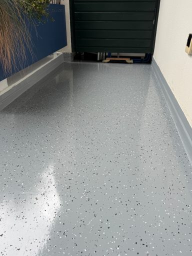 Grau glänzender Boden mit speckiger Oberfläche in einem geschlossenen Raum.