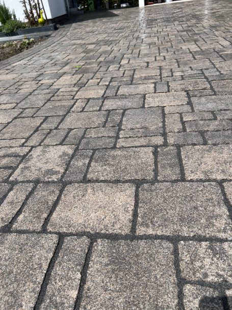 Ein gepflasterter Weg mit großen, hellen und dunklen Steinplatten.